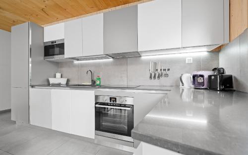 a kitchen with white cabinets and a stove top oven at Aparthotel Zell am See (Contactless Check-In) in Zell am See