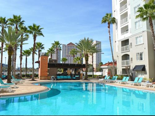 a large swimming pool with palm trees and chairs at The Point Hotel & Suites Universal in Orlando