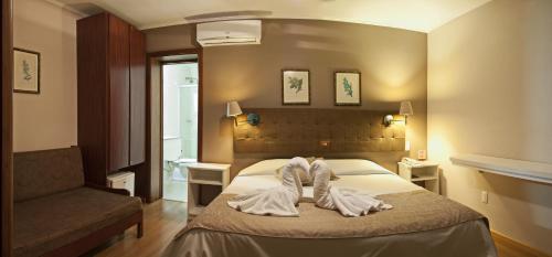 um quarto de hotel com uma cama com toalhas em Pousada Bernardete - No coração de Gramado em Gramado