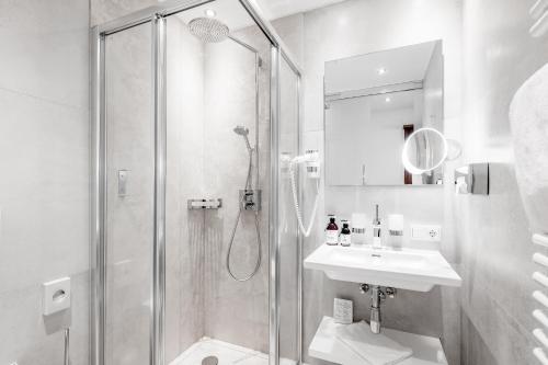 a white bathroom with a shower and a sink at SKI - GOLF - WELLNESS Hotel Riml in Hochgurgl