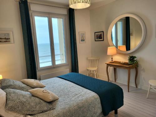 een slaapkamer met een bed en een groot raam bij L'Hermitage, villa front de mer in Pirou