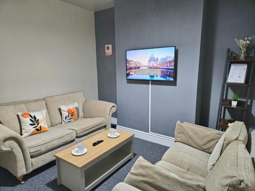 a living room with two couches and a flat screen tv at spacious luxury near city center free parking in Coventry