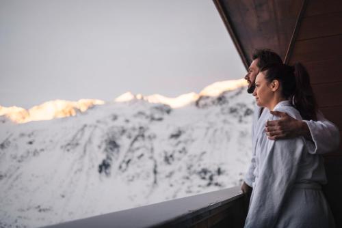 a woman standing next to a window with snow at SKI - GOLF - WELLNESS Hotel Riml in Hochgurgl