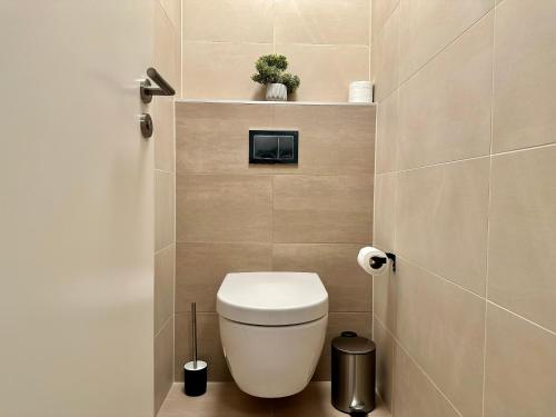 a bathroom with a toilet with a plant on a shelf at Vivien Modern City in Brno