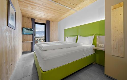 a bedroom with a large bed with a green headboard at Aparthotel Zell am See (Contactless Check-In) in Zell am See