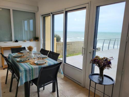 une salle à manger avec une table et une vue sur l'océan dans l'établissement L'Hermitage, villa front de mer, à Pirou