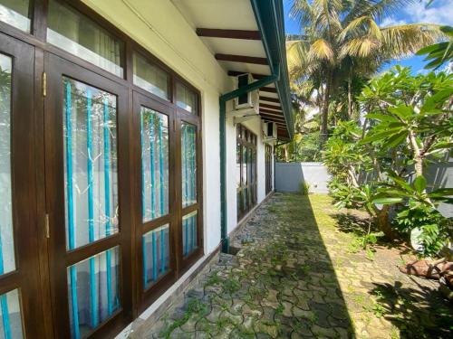 - une vue sur l'extérieur d'une maison avec des portes en verre dans l'établissement Lady Nelly villa Hikkaduwa, à Hikkaduwa