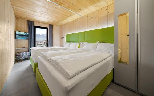 a bedroom with two large beds with a green headboard at Aparthotel Zell am See (Contactless Check-In) in Zell am See
