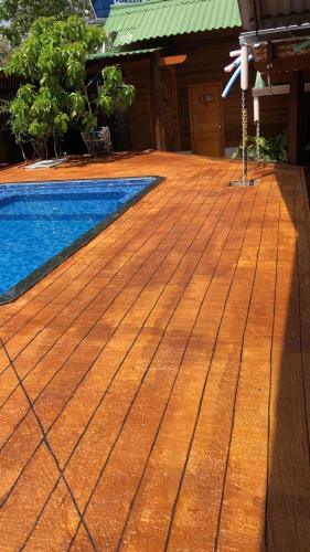 a swimming pool with a wooden deck next to a house at Pousada Rekantu do Poeta in Alter do Chao