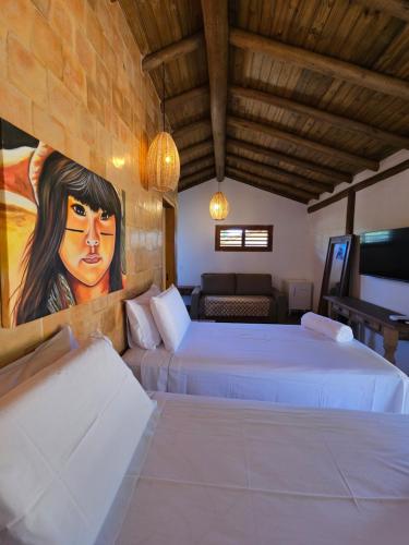 a bedroom with two beds and a painting on the wall at Tawa Caraíva in Caraíva