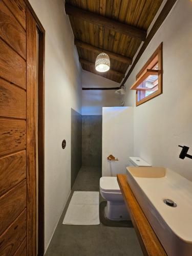 a bathroom with a white toilet and a sink at Tawa Caraíva in Caraíva