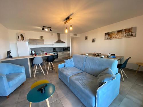 un salon avec un canapé bleu et une cuisine dans l'établissement Appartement Le Frassu PORTICCIO, à Porticcio