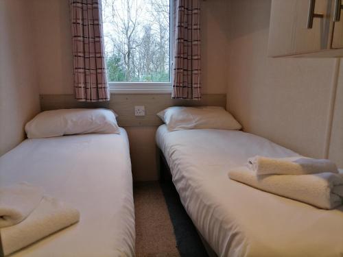 2 Betten in einem kleinen Zimmer mit Fenster in der Unterkunft Victory - idyllic holiday home in Hastings in Hastings