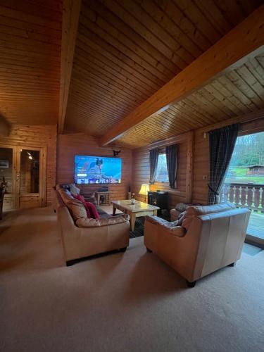 a living room with two couches and a flat screen tv at Kipplochan in Dalbeattie