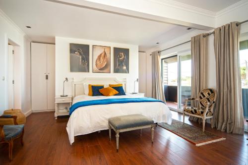 a white bedroom with a bed and a chair at Marigold Cascais Villa in Cascais