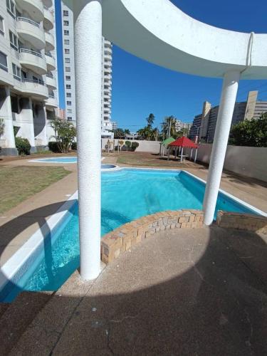 a swimming pool next to a large apartment building at LagunaSuite & More in Porlamar