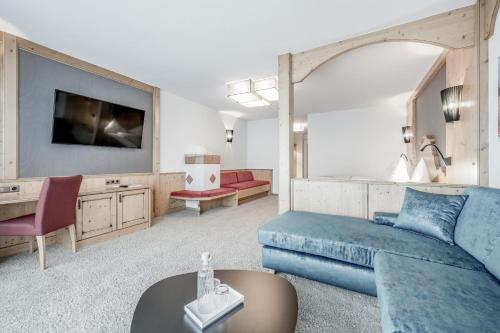 a living room with a blue couch and a tv at SKI - GOLF - WELLNESS Hotel Riml in Hochgurgl