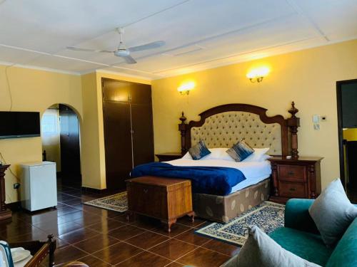 een slaapkamer met een groot bed en een bank bij The White House of Victoria Falls in Victoria Falls
