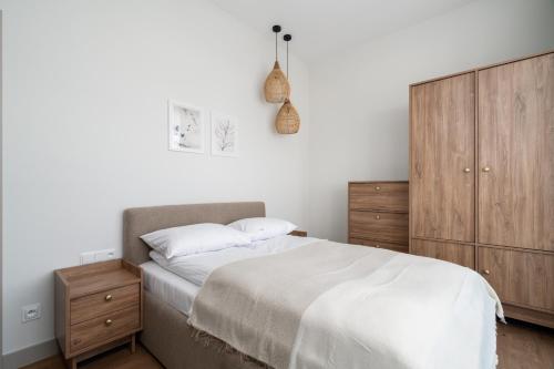 um quarto com uma cama e um armário de madeira em Stylish Beige Apartment with One Bedroom and Parking in Poznań by Renters em Poznań