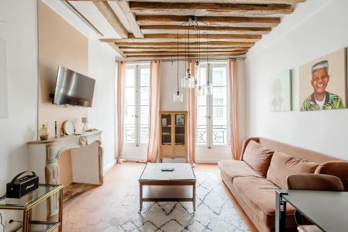 uma sala de estar com um sofá e uma mesa em Le Clos St Louis em Paris