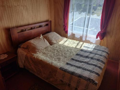 Una cama con una manta en una habitación con ventana en Casa Orilla de Mar, en Quellón
