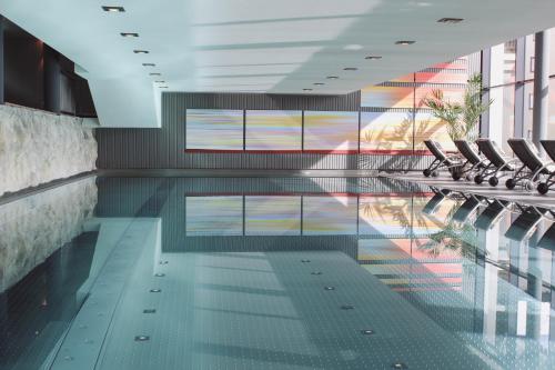 a swimming pool with chairs in a building at SKI - GOLF - WELLNESS Hotel Riml in Hochgurgl