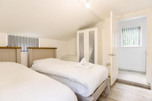 a white bedroom with two beds and a window at Caerau Gardens in Newport