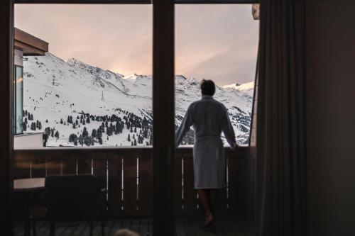 a person looking out a window at a snow covered mountain at SKI - GOLF - WELLNESS Hotel Riml in Hochgurgl