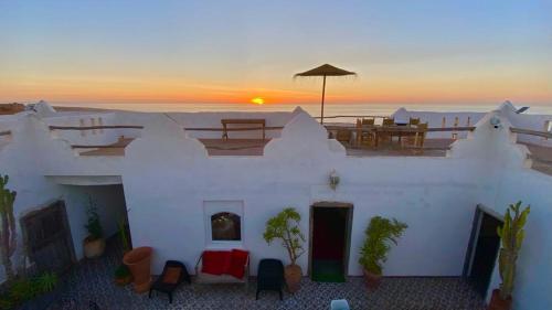 a white building with a sunset in the background at Riad Sahara Sunset Beach Agadir in Douaïra
