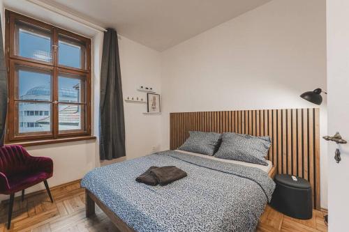 a bedroom with a bed and a chair and a window at Carolina's Yoga apartment in Hradec Králové