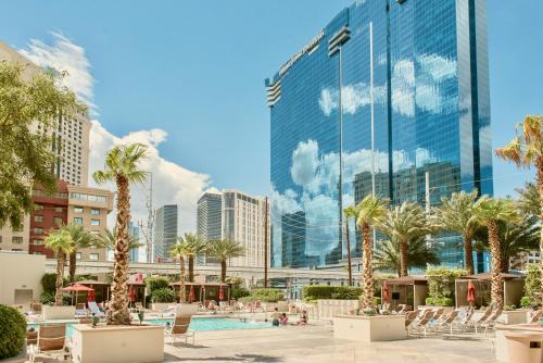 a view of a pool with palm trees and buildings at Strip View Suites - No Resort Fee ! in Las Vegas