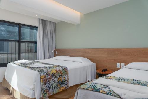a hotel room with two beds and a window at Vistamar Hotel in Maceió