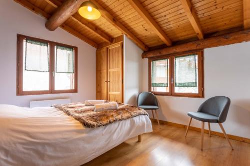 a bedroom with a large bed and two chairs at Le petit Paradis, chalet au coeur des 3 vallées in Saint-Marcel