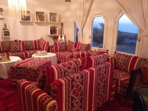 a room with red chairs and tables and windows at Riad Sahara Sunset Beach Agadir in Douaïra