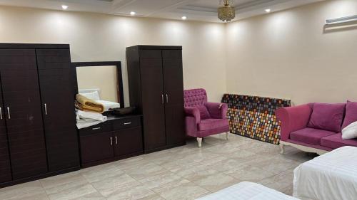 a bedroom with purple furniture and a mirror and purple chairs at نزل الخالدية in Al Qunfudhah