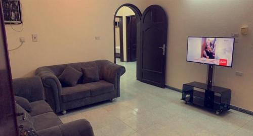 uma sala de estar com um sofá e uma televisão de ecrã plano em نزل الخالدية em Al Qunfudhah
