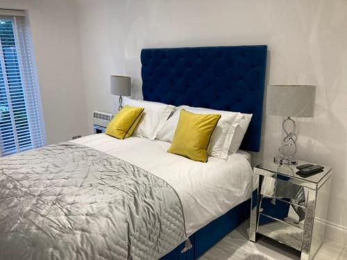 uma cama com cabeceira azul e almofadas amarelas em Hertford fabulous 2 bed garden apartment em Hertford