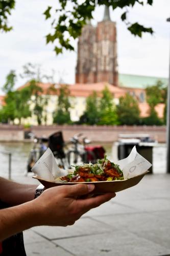 a person is holding a plate of pizza at DoubleTree by Hilton Wroclaw in Wrocław