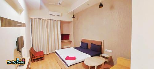 a bedroom with a bed and a table and a tv at Taj Suites & Studios-Top Place Couple Friendly Stay at Luxury Gaur City Mall #Movie, #Food Court #Shopping in Ghaziabad