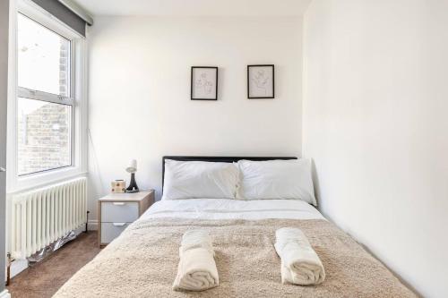 een witte slaapkamer met een bed en een raam bij Charming 3-Bed Apartment in London in Londen