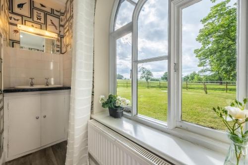 a bathroom with a window with a view of a field at The Gate House in Wymondham