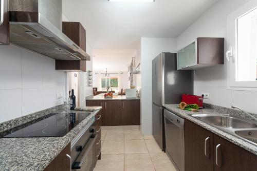 a kitchen with wooden cabinets and a stainless steel refrigerator at Impresionante Villa Son Ganxo II en Cala Murada! in Cala Murada