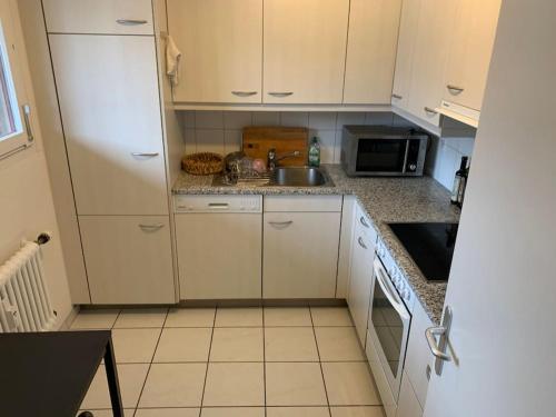 a kitchen with white cabinets and a sink at Cozy Flat in the Center of Kleinbasel in Basel