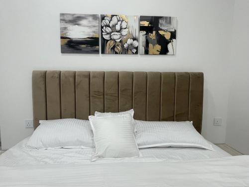 Una cama con sábanas blancas y dos cuadros encima. en AL Rabie Resort ,Nizwa Grand Mall en Firq