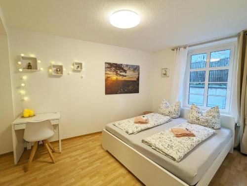 a bedroom with a bed and a desk and a window at HW2B - Urlaubsmagie - Wohlfühlwohnung mit Balkon, Pool, Sauna & Terrasse in Sebnitz