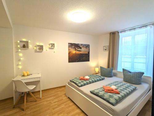 a bedroom with two beds and a desk and a window at HW2B - Urlaubsmagie - Wohlfühlwohnung mit Balkon, Pool, Sauna & Terrasse in Sebnitz