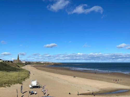 a beach with people on the sand and the ocean at Longsands Beach, Apartment 3, Tynemouth in Tynemouth