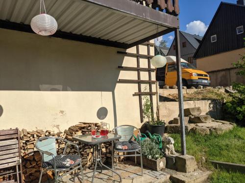 a patio with a table and chairs and a yellow van at HW2B - Urlaubsmagie - Wohlfühlwohnung mit Balkon, Pool, Sauna & Terrasse in Sebnitz
