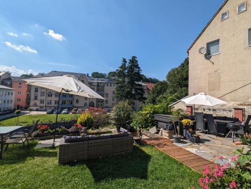 a garden with tables and chairs and umbrellas at HW2B - Urlaubsmagie - Wohlfühlwohnung mit Balkon, Pool, Sauna & Terrasse in Sebnitz