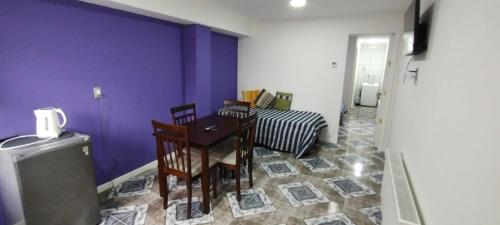a room with a table and chairs and a purple wall at Departamento Nuevo in Punta Arenas